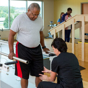 A physical therapist helping a man walk.