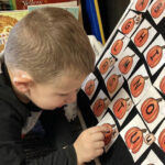a young boy counting paper pumpkin drawings