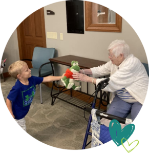 a child showing his stuffed animal to an elderly woman